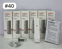 Set of 6 DSC PowerG Wireless Shock Sensors in original packaging with one sensor out of box, mounting hardware, battery and manual included.