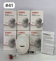 Six DSC branded boxes stacked with one detector, battery, screws, and manual displayed in front showing included contents.