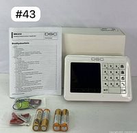 DSC WK250 keypad with user manual, four batteries, mounting screws and anchors, and three wireless key fobs displayed on white background with lot number #43 visible.