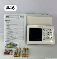 Full kit showing DSC WK250 keypad, user manual in Finnish, batteries, three key fobs, and mounting hardware.