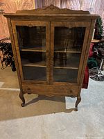 Full view of the antique hutch showing glass doors, queen anne legs, and overall wood finish.