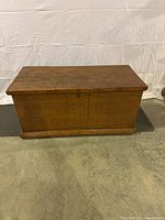 Front view of antique wooden blanket box showing closed top and rectangular shape with patina.