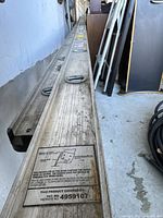 Close-up of the ladder's side rail showing detailed patent and usage instructions label.