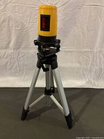 Johnson laser level mounted on telescoping tripod with black feet and adjustable base