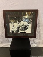 Framed black and white photograph showing two hockey players in Team Canada jerseys, framed in dark wood with double matting.
