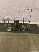 Full set of all washroom hardware pieces displayed together on a mat, showing two towel holders, waste bin, soap dishes, toothbrush holder, and soap dispenser stands.