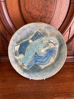 Front view of charger plate showing abstract blue-green glazed design