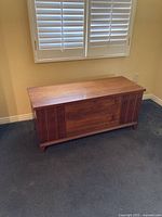 Front view of walnut hope chest closed, showing facade with vertical inlays and bracket feet.