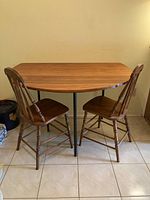 Full view of handmade solid wood semi-circle table with two wooden chairs on either side, showing table shape and chair style.