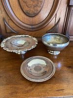 Three silver and silver plated dishes displayed together on wooden surface