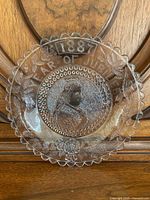 Clear glass plate with scalloped edge. Etched central portrait of Queen Victoria and the text '1887 YEAR OF JUBILEE' around the rim with floral motifs.
