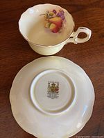 Tea cup with fruit and lilac design, no maker's mark, paired with plain saucer