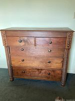 Front view showing two small top drawers above three full-width drawers and turned spindle columns