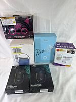Full front view of the lot boxes including the packaged LED cat ears headset, evaporator fan, mouse hair removal system, Netgear Wi-Fi range extender, and two gaming mice boxes.