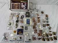 Overview of the assortment showing multiple vintage sports pins arranged by type with some baseball cards in box