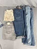 Six pieces of women's denim clothing including jeans and cutoff shorts in various washes and colors.
