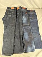Four pairs of men's Levi's denim jeans folded and laid out side by side, showing overall color and condition differences.