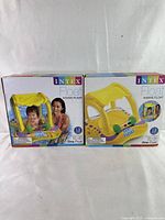 Front view of two sealed Intex kiddie float boxes featuring yellow inflatable baby floats with canopies and colorful printed designs showing a baby and adult using the float in water.