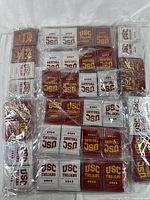 Top-down image of 40 sealed USC Trojans official playing card decks, showing both maroon and white decks packed in groups.