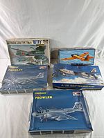 Front view of all five vintage airplane model kits in original boxes showing box artwork and condition