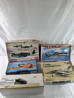 Five vintage airplane model kits in boxes arranged together, showing various airplane models and wear on packaging.