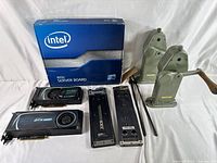 Photo showing full lot including Intel server board box, two EVGA graphics cards, metal camera film rewinders, and mounting brackets.