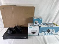 Overview of the DVR unit, power adapter, mouse, and three camera boxes against a plain background.