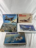 Five vintage airplane plastic model kit boxes arranged on white surface, showing box art and titles.