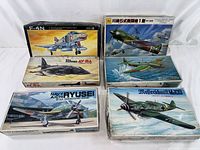 Six vintage airplane model kits arranged in two stacks, showcasing illustrated box art for each model.