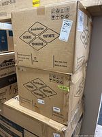 Two stacked cardboard boxes containing Kidol & Shellder bar stools. Top box has Macdonalds sticker showing price $250 each.