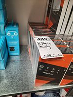 Shelf display showing multiple Ledger Nano X boxes with a label indicating '8 Bitcoin Security'.