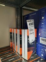 Five sealed boxes of Ledger Nano X hardware wallets arranged on metal shelf