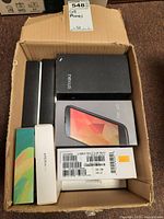 Box containing multiple branded cell phone boxes including Nexus, Xperia, and others.