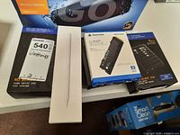 Tabletop with several Western Digital WD_BLACK storage drives in sealed retail boxes and a white Apple Pencil box