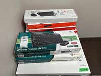 Stack of six keyboard boxes showing brands Microsoft and Logitech, models include Sculpt Comfort, Wireless Desktop MX710, and Wireless Combo MK320.