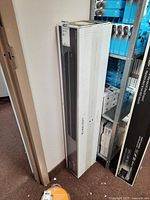 Sealed Samsung soundbar box leaning against wall and shelving