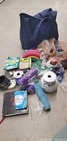Wide view of all items showing ribbons, rolls of mesh, a pink flexible circular frame, navy tote bag, and some floral craft supplies.