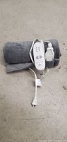 Full view of rolled blue electric blanket with attached white controller and power cord.