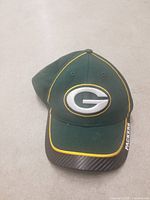 Green Bay Packers baseball cap showing front embroidery, green color, yellow piping, and branded brim.
