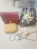 Two bags, a small tan pouch, and a plugged-in heart-shaped salt lamp