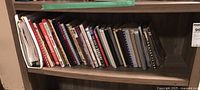 Shelf with assorted cookbooks and manuals, showing condition and variety