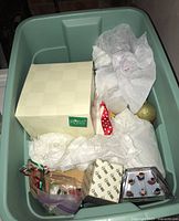 Photo of a Rubbermaid storage tote filled with wrapped Christmas ornaments, boxes labeled Fossil and others, and tissue paper protecting items