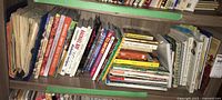 Bookshelf with several cookbooks, some showing wear and aging, including larger paperbacks and various titles.