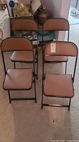 Four brown vinyl padded folding chairs with black metal frames, viewed from front and top angles.