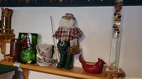 Photo shows Fisherman Santa doll, Galileo thermometer, red ceramic cardinal candle holder, and additional candle holders in background.