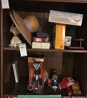 Lot contents on shelves showing two straw hats, dog figurine, model kit, tripod lamp, and assorted hobby items.