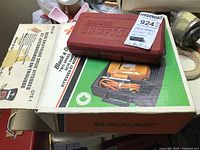 Black & Decker jigsaw in original packaging on bottom, Sears Craftsman red socket set case on top