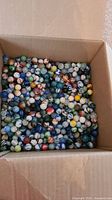 Cardboard box filled with assorted glass marbles