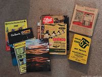 Photo showing a group of nine vintage catalogs arranged on the floor, colorful and with visible different titles including 'Joe Bealer Savings', 'Eatons Wrapper Specials', and others.