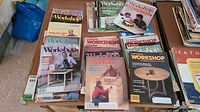 Overview of multiple stacked Canadian Workshop magazines spread on tables.